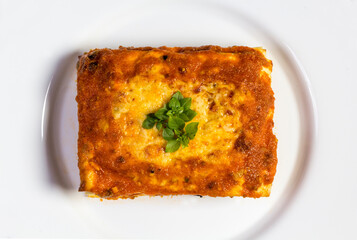 slice of bolognese lagna with tomato sauce and cheese on top and served on a white plate. Top view
