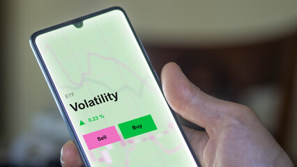 An investor's analizing the volatility etf fund on a screen. A phone shows the prices of Volatility