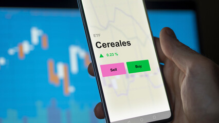 An investor's analizing the cereales etf fund on a screen. A phone shows the prices of Cereales