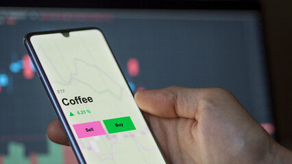An investor's analizing the coffee etf fund on a screen. A phone shows the prices of Coffee