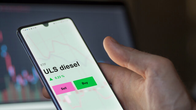 An investor's analizing the uls diesel etf fund on a screen. A phone shows the prices of ULS diesel