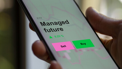 An investor's analizing the managed future etf fund on a screen. A phone shows the prices of Managed future
