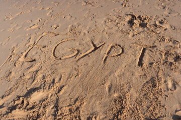 Fototapeta na wymiar Egypt title written on the wet sand beach on sunny afternoon. Selective focus