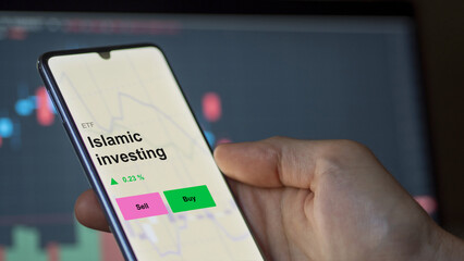 An investor's analizing the islamic investing etf fund on a screen. A phone shows the prices of Islamic investing