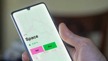 An investor's analizing the space etf fund on a screen. A phone shows the prices of Space