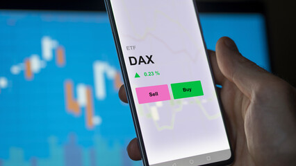 An investor's analizing the dax etf fund on a screen. A phone shows the prices of DAX - obrazy, fototapety, plakaty