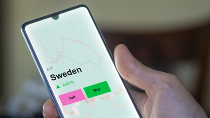 An investor's analizing the sweden etf fund on a screen. A phone shows the prices of Sweden swedish market ETF. 