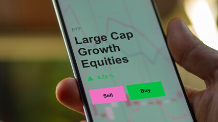 An investor's analizing the large cap growth equities etf fund on a screen. A phone shows the prices of largeCap equity. 