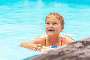 Beautiful cute little girl swims in the outdoor pool with an inflatable ring