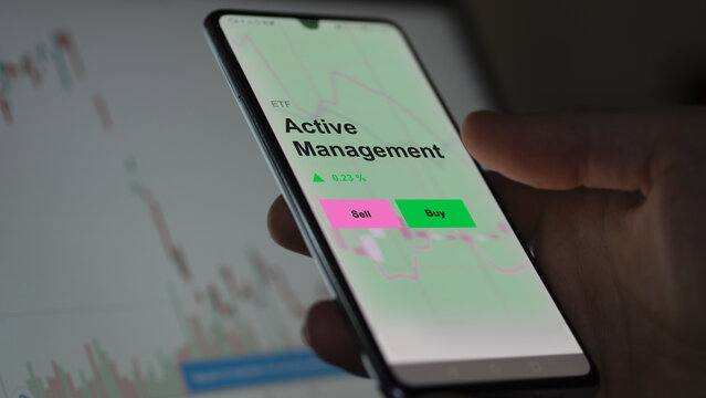 An Investor's Analizing The Active Management Etf Fund On A Screen. A Phone Shows The Prices Of Active Management