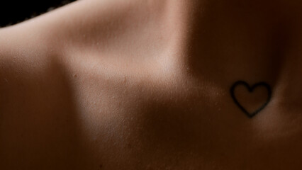 Extreme close-up shot of good-looking slim young white-skinned female model's clavicle on black background | Skin texture shot for body moisturizing concept