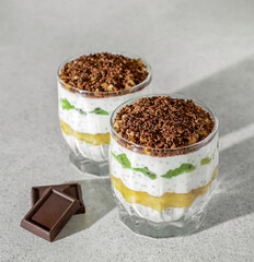 Healthy and delicious breakfast in glass cups, layers of kiwi, banana and chia seeds in chocolate shavings