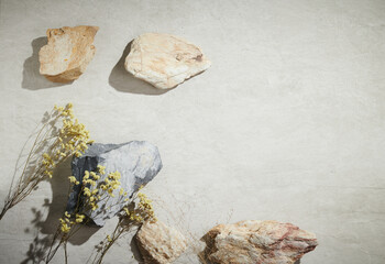 Flatlay minimal natural stone, marble or travertino surface background with stones and dry flowers....