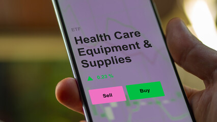 An investor's analizing the health care equipment & supplies etf fund on a screen. A phone shows the prices of Health Care Equipment & Supplies