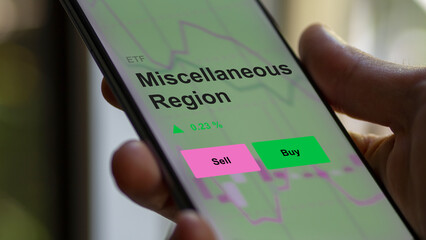 An investor's analizing the miscellaneous region etf fund on a screen. A phone shows the prices of diverse various regions