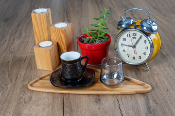 Obraz na płótnie Canvas Turkish coffee concept, turkish coffee cup, glass water glass, bamboo plate, green plant with red pot, on wooden table, diagonal view, Candle Holder Cone