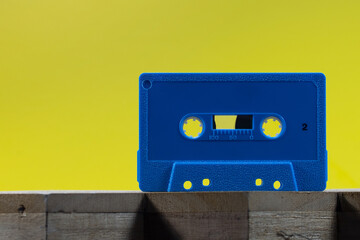 Blue Cassette on a wood surface with a yellow background