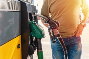 A man at the gas station filling the tank of his car with diesel to the top level before a long...