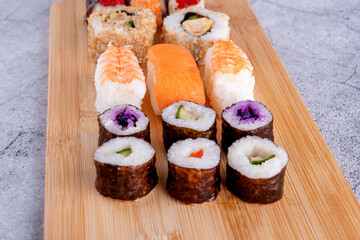 sushi set  with chopsticks and soy on a wooden plate ready to eat on grey background