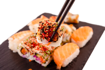 sushi set  with chopsticks and soy on a wooden plate ready to eat on grey background