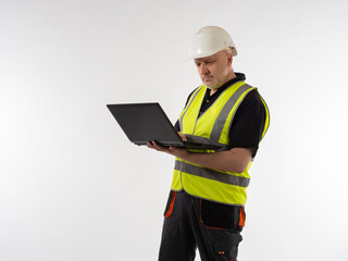 Engineer with a laptop in his hands. Worker wearing white safety helmet and reflective vest. Worker with a laptop in his hands. Engineer in a working uniform. Man sets up the equipment using a laptop
