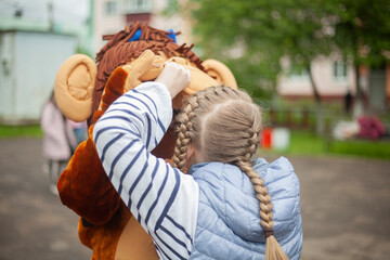 Naklejka premium Child plays with growth doll. Animator at festival entertains children. Girl holds man in monkey costume. Rest in park.