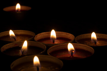 Round candles burn in dark. Wax candles on dark background. Red and yellow lights.