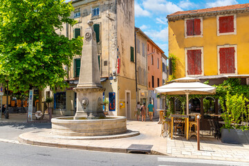 The Fontaine de Mirabeau drinking fountain with obelisk in the medieval old town of the idyllic town of Saint-Remy-de-Provence, in the Provence Cote d'Azur region of France on a summer day.