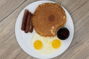Overhead view of standard American breakfast consisting of pancakes, fried eggs, and sausage will ensure that the belly will be full