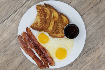 Overhead view of traditional American breakfast consisting of french toast, fried eggs, and bacon will ensure that the belly will be full