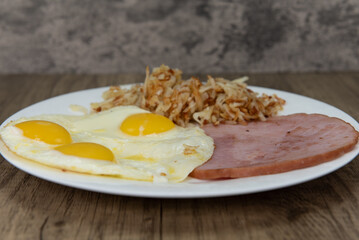 Standard American breakfast consisting of ham, fried eggs, and hash browns will ensure that the belly will be full