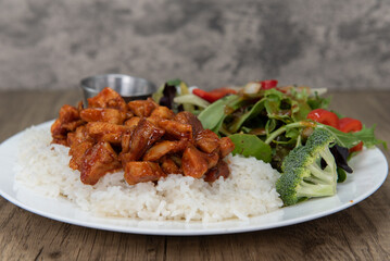 Tempting Chinese cuisine meal consisting of spicy chicken over rice with vegetables will ensure that the belly will be full