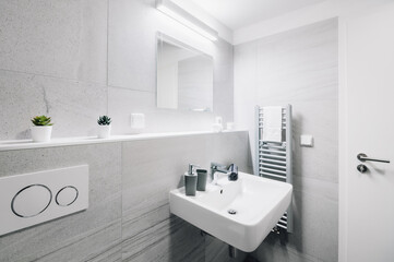 A small modern bathroom with a large mirror, square sink, toilet and glass shower enclosure. There...