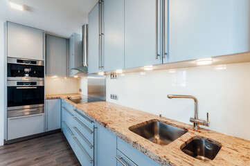 Large luxury kitchen unit made of light blue laminate, glass and marble. It is equipped with...