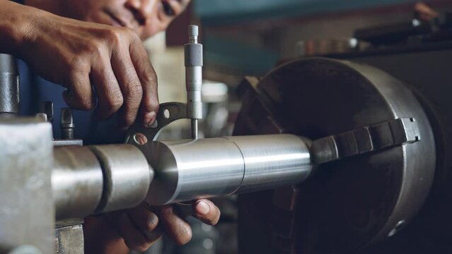 Technician asia worker using vernier caliper measure detail of workpiece for checking size in workshop lathe machine factory