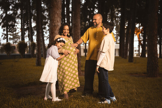 latin family in pine forest with pregnant mom, dad, boy and girl