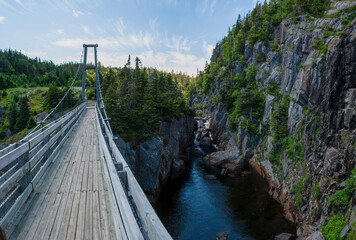 The reconstructed suspension bridge of the ghost town of La Manche, Newfoundland crosses over the...