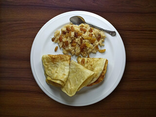 Delicious hand made fried paratha with semolina and fork on  wooden table. Top view of Asian food dish.