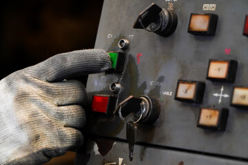 Dirty gloves press the green start button on the CNC machine control panel.