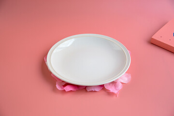 Pink background, white round plate, fork, knife
