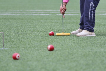 Athlete play balls for gateball game to beat competitors in a field lawn