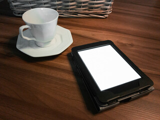 E-book reader and cup on the table.