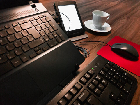 Laptop, coffee cup, e-book reader, keyboard and mouse.