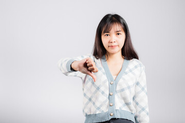 Unhappy woman smile show finger thumbs down rejection unlike, Portrait Asian beautiful young female negative gesture showing finger thumbs down or dislike sign studio shot isolated on white background