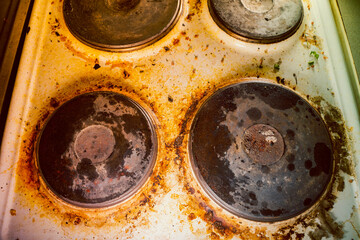 Old kitchen electric stove in heavy brown pollution and soot close-up, top view