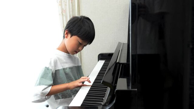 アップライトピアノを弾く日本人の男の子