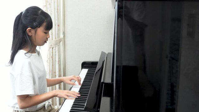 アップライトピアノを弾く日本人の女の子