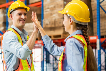 Colleague workers in warehouse factory have a greeting by high five with hands raised up at factory...