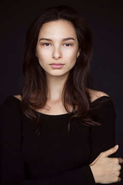 Front Closeup Portrait Of A Young And Cute Beautiful Black Long Hair Woman Pose With Self-confidence On Black Background.