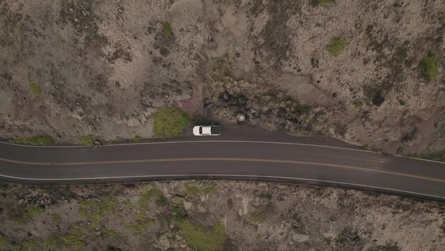 A twisting downward aerial zooming into a parked car on the side of an ancient Hawaiian lava field.  The starting place for a story set in Maui, Hawaii.  A Garden of Eden until you have car problems.
